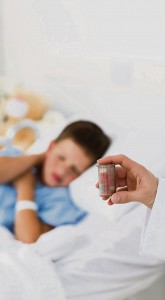 Doctor holding pill bottle with boy in ward